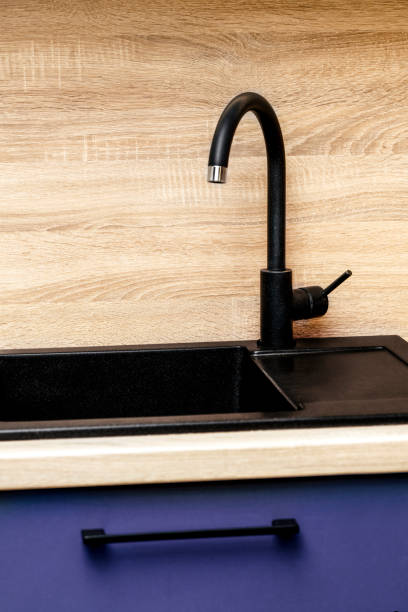 istock Modern Black Kitchen Faucet and Sink Against a Wooden Backsplash 2205245974