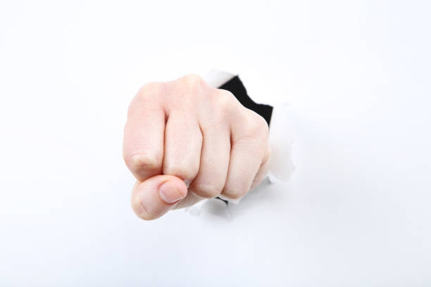 istock Hand shows fist from white torn paper 2205247892
