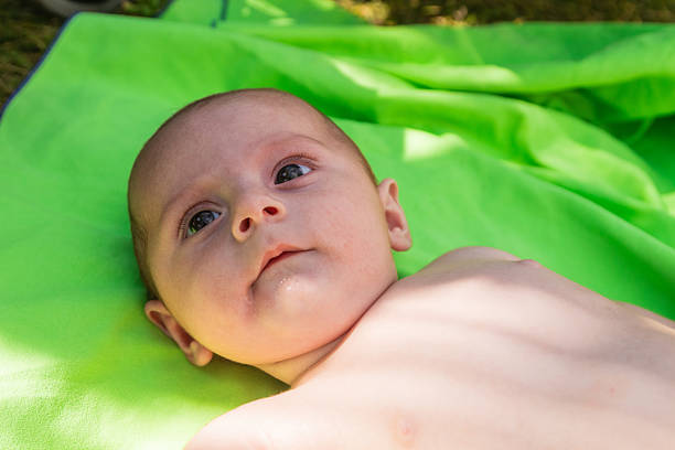 Adorable baby lying on a soft green towel, enjoying a moment of relaxation after bath time
