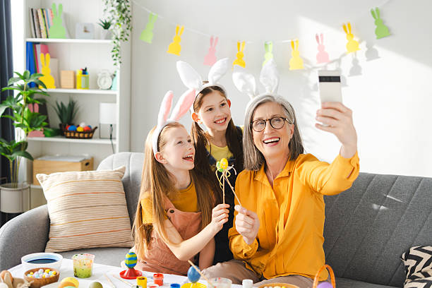 istock Smiling, happy grandmother and granddaughters taking easter selfie while painting eggs 2205248251
