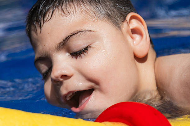 istock Child with cerebral palsy enjoying swimming pool fun 2205248304