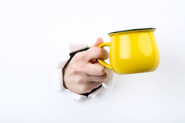 istock Hand holding yellow mug from white torn paper 2205248540
