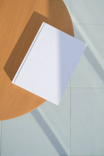 istock book cover mockup design. blank book mockup on wooden coffee table , shadow overlay 2205248629
