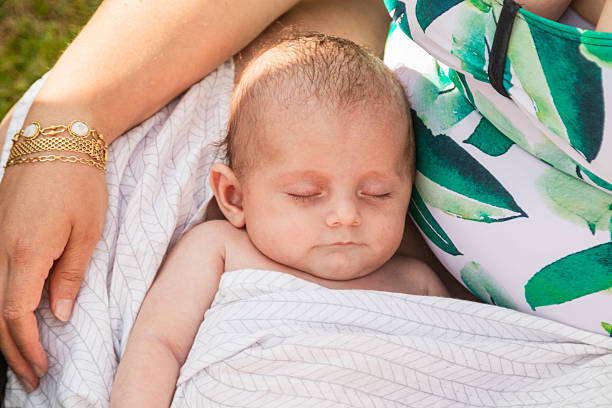 istock Serene baby sleeping peacefully in mother's arms by the pool 2205249413