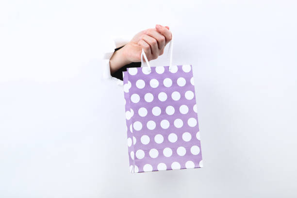 Hand holding shopping bag from white torn paper