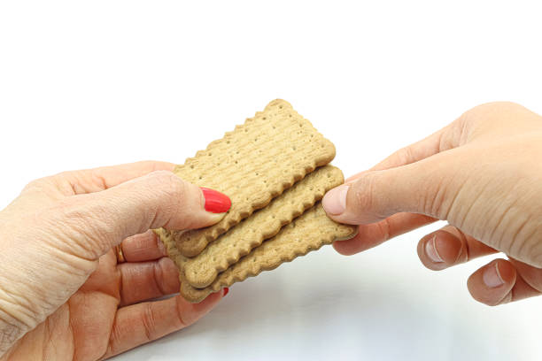 Woman's hand offering some cookies to a boy, on white background.