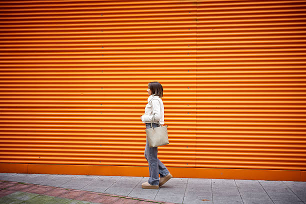 istock Woman walking on orange background 2205252363