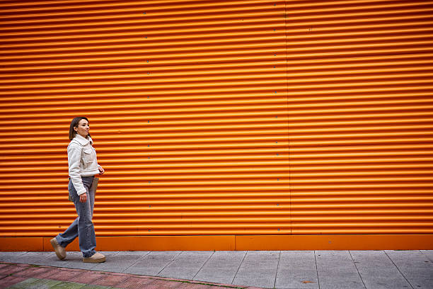 istock Woman walking on orange background 2205252385