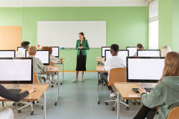 istock Female teacher talking to university students during lesson in computer lab 2205260746