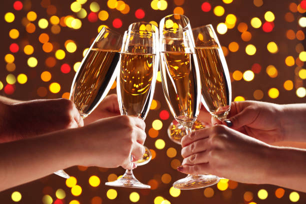 istock Hands holsing champagne glasses on lights background 2205262499