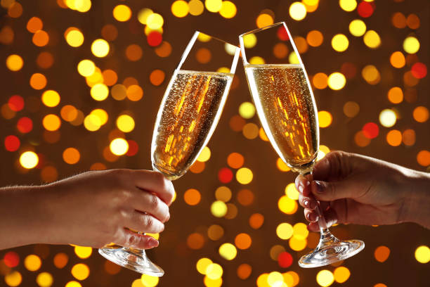 istock Hands holsing champagne glasses on lights background 2205262578