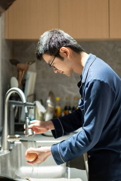 istock An Asian man washing an apple in the kitchen 2205264757