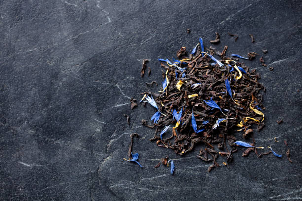Earl grey loose leaf tea blend with cornflower and orange blossom petals. Marble background. Copy space. Top view.