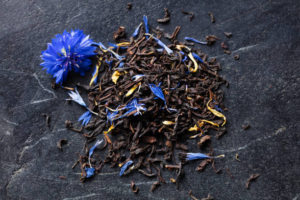 istock Earl grey loose leaf tea blend with cornflower and orange blossom petals on dark marble board. Close up. Top view. 2205270576