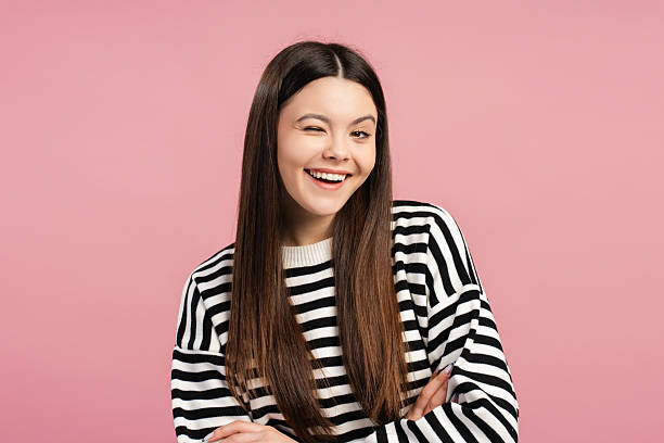 istock Cheerful young girl winking and smiling on pink background 2205287827
