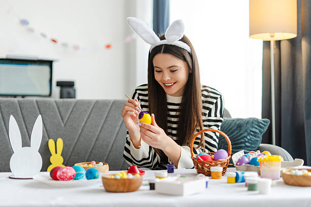 istock Young smiling attractive girl painting easter eggs at home 2205287864