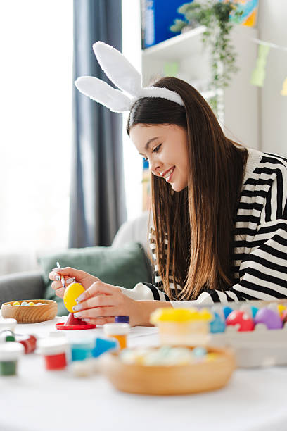 istock Cheerful beautiful girl painting easter eggs at home 2205287872