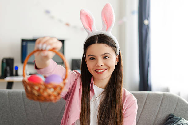 istock Happy young girl showing easter eggs basket wearing bunny ears 2205287879