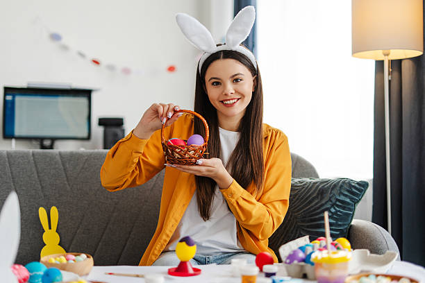istock Attractive girl showing basket with easter eggs at home 2205287882