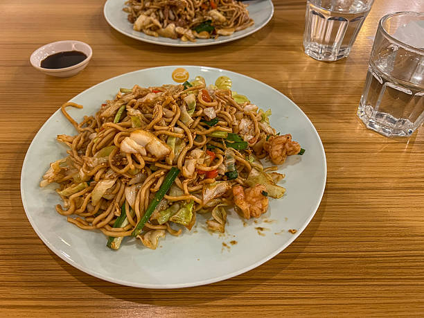 istock Fried noodle with shrimp and vegetables in white plate on wooden table 2205290304
