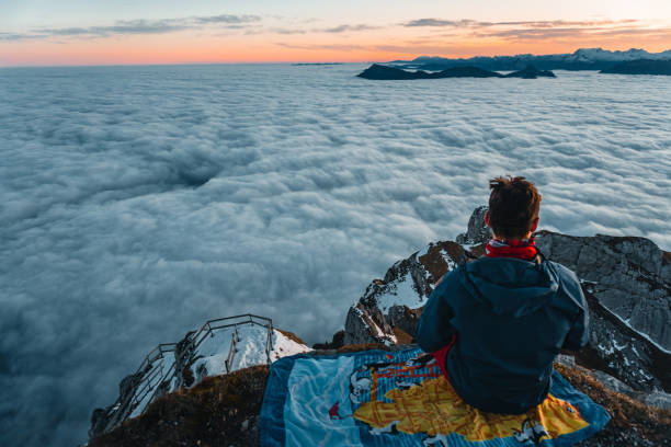 istock Man sits on mountain top at sunrise 2205294309