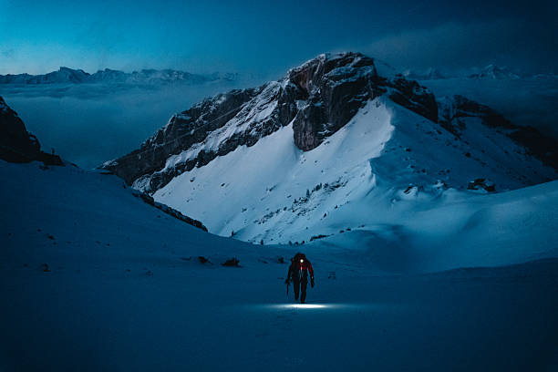 Mountaineer climbs to mountain summit at dusk