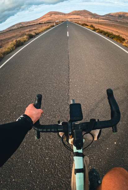 istock View past road cyclist bicycle looking down road at sunrise 2205299444