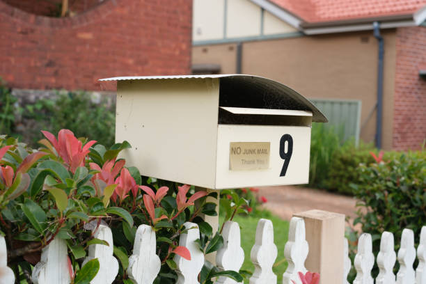 Chose-up on a cream colored metal mailbox with a no junk mail sign.