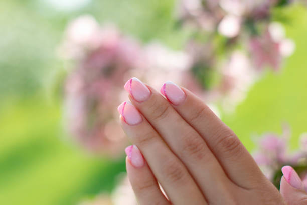 Beautiful female hand with pink manicure nails on flower background