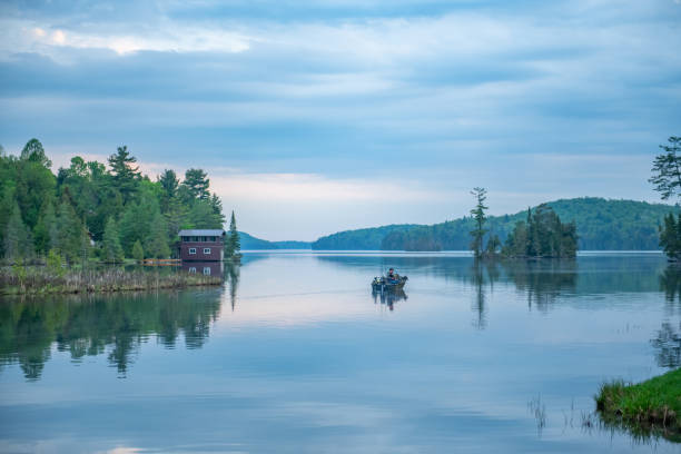 Overcast day on a calm lake with a fisherman in a boat heading out to fish