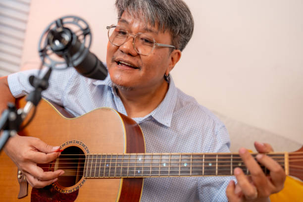 istock man playing acoustic guitar and singing into microphone, creating joyful atmosphere. His passion for music is evident as he strums strings 2205313502