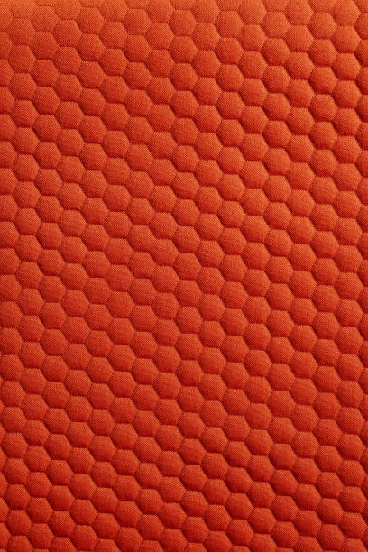 This image is a detailed macro shot of a bright orange fabric. The texture features a pattern of repeating hexagons, creating a geometric design throughout.