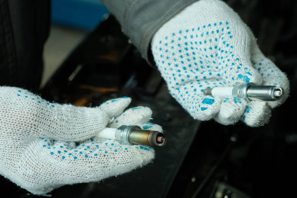 An auto mechanic demonstrates a faulty spark plug and prepares the installation of a new spark plug.spark plugs.