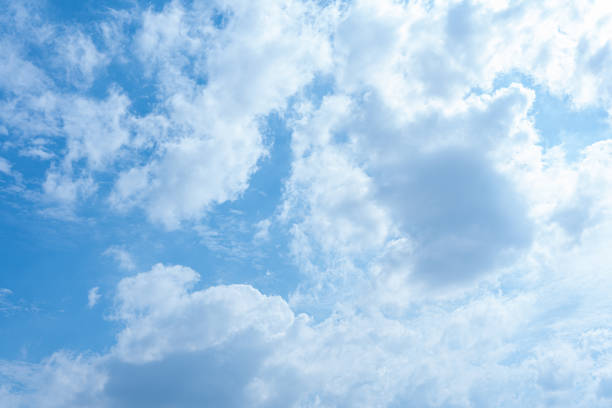 A stunning image of a bright blue sky filled with fluffy white cumulus clouds Ideal as a background for various designs or projects this image evokes a feeling of serenity and peace  The bright lighting and soft cloud formations create a captivating natural scene