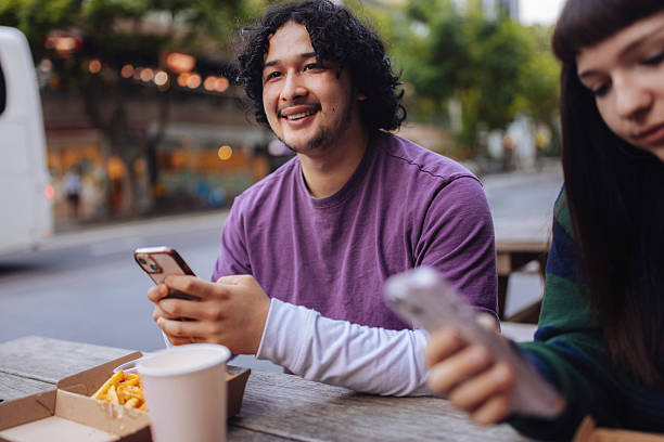istock Teeange boy texting messages at street restaurat 2205323315