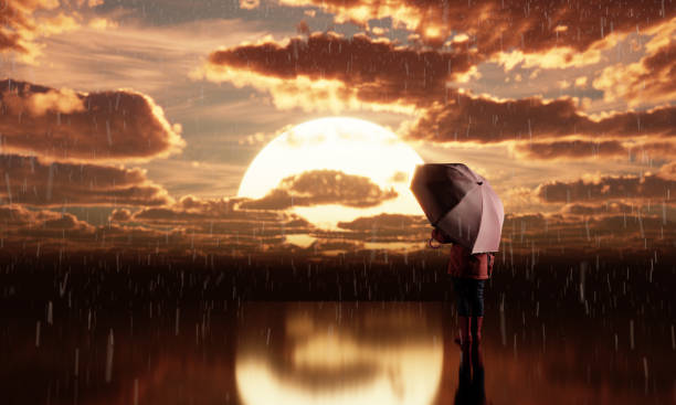 Young girl with umbrella watching the sunset