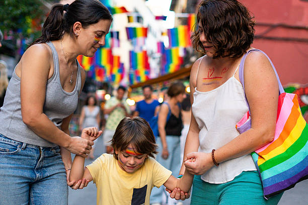 istock Lesbian mothers holding hands with their child at pride parade 2205338818