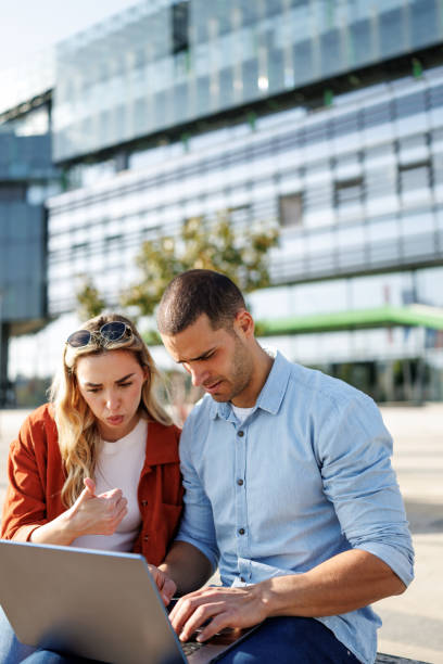 istock Young business couple using laptop together outside office building 2205338942