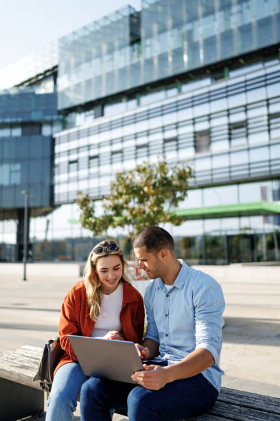 istock Young business couple using laptop together outside office building 2205339670