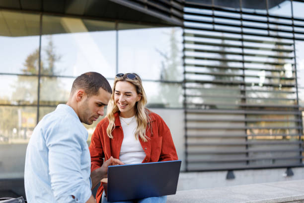 istock Young business couple using laptop together outside office building 2205339760