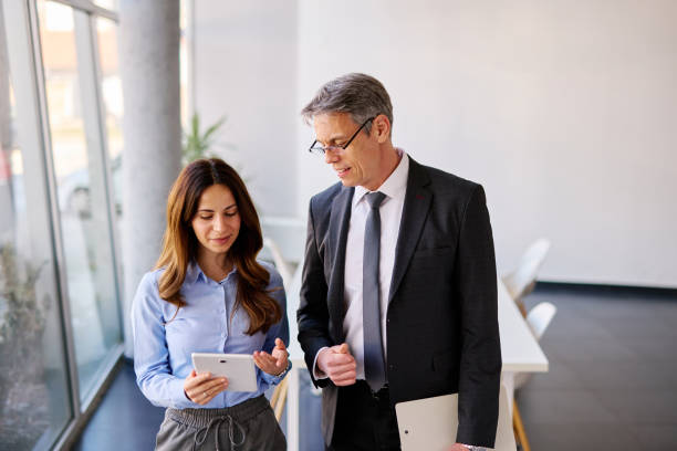 istock Businesspeople walking and discussing using digital tablet in modern office 2205341986