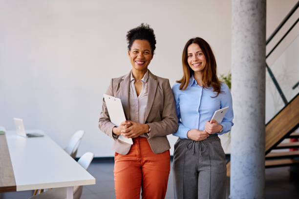 istock Two smiling businesswomen standing in modern office 2205342055