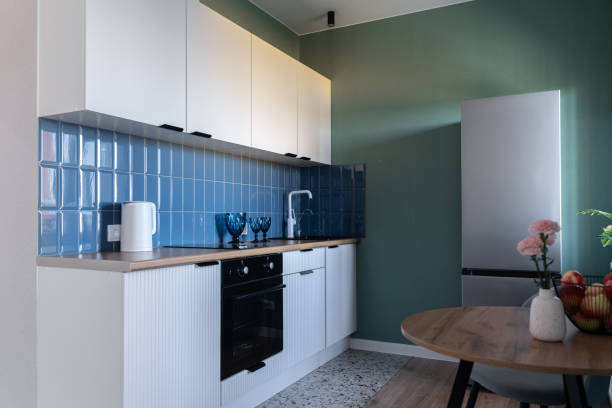 istock design of modern small kitchen. built-in kitchen with white cabinets, blue tile backsplash, wooden countertop. white kitchen unit. steel refrigerator, oven, flowers on vase, white faucet 2205342298