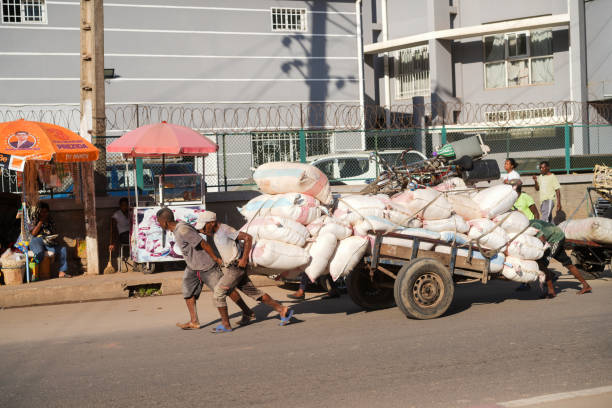 Antananarivo, Madagascar - 24 April, 2024: Four man powered truck. A large horse-drawn carriage filled with bags being pushed by four people on a large shopping street in the business district.