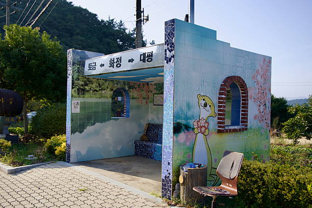 Gurye County, South Korea - October 3, 2021: A uniquely decorated bus stop featuring a vibrant otter mural and mosaic designs, offering a charming rest spot along a rural road in the Korean countryside.