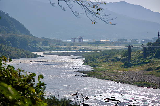 Gurye County, South Korea - October 3rd, 2021: Sunlight shimmers on the surface of the Seomjin River, winding through the valley with distant bridge construction marking ongoing infrastructure development.
