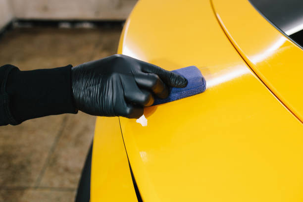 istock Process of apply ceramic layer on body car using sponge close-up in detailing auto service. Hand applying of nano ceramic protective coat to protect car from scratches. 2205351944