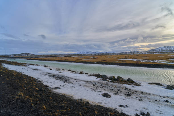 Turquoise river flowing through a snow covered landscape with mountains in the background