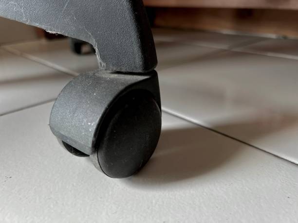 istock Single Black Wheel of a Wheelchair Casting a Shadow on White Tiled Floor 2205366145