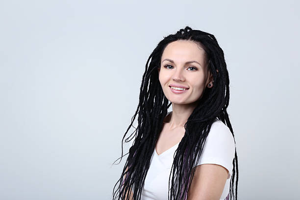 Cute young woman with dreadlocks on grey background